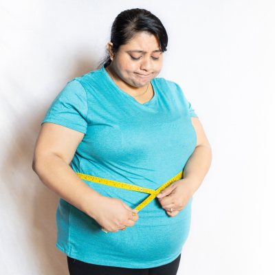 A fat woman measuring her waist illustrates obesity.
